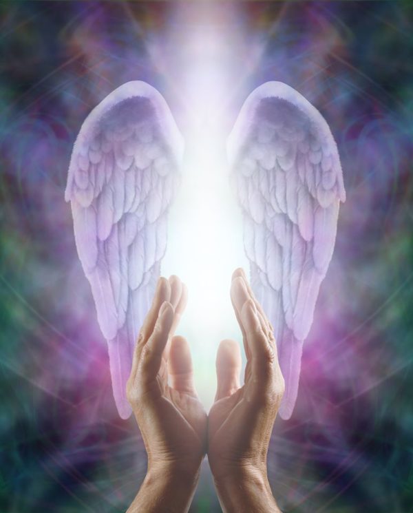 A pair of hands with angel wings providing spiritual healing in front of a colorful background.