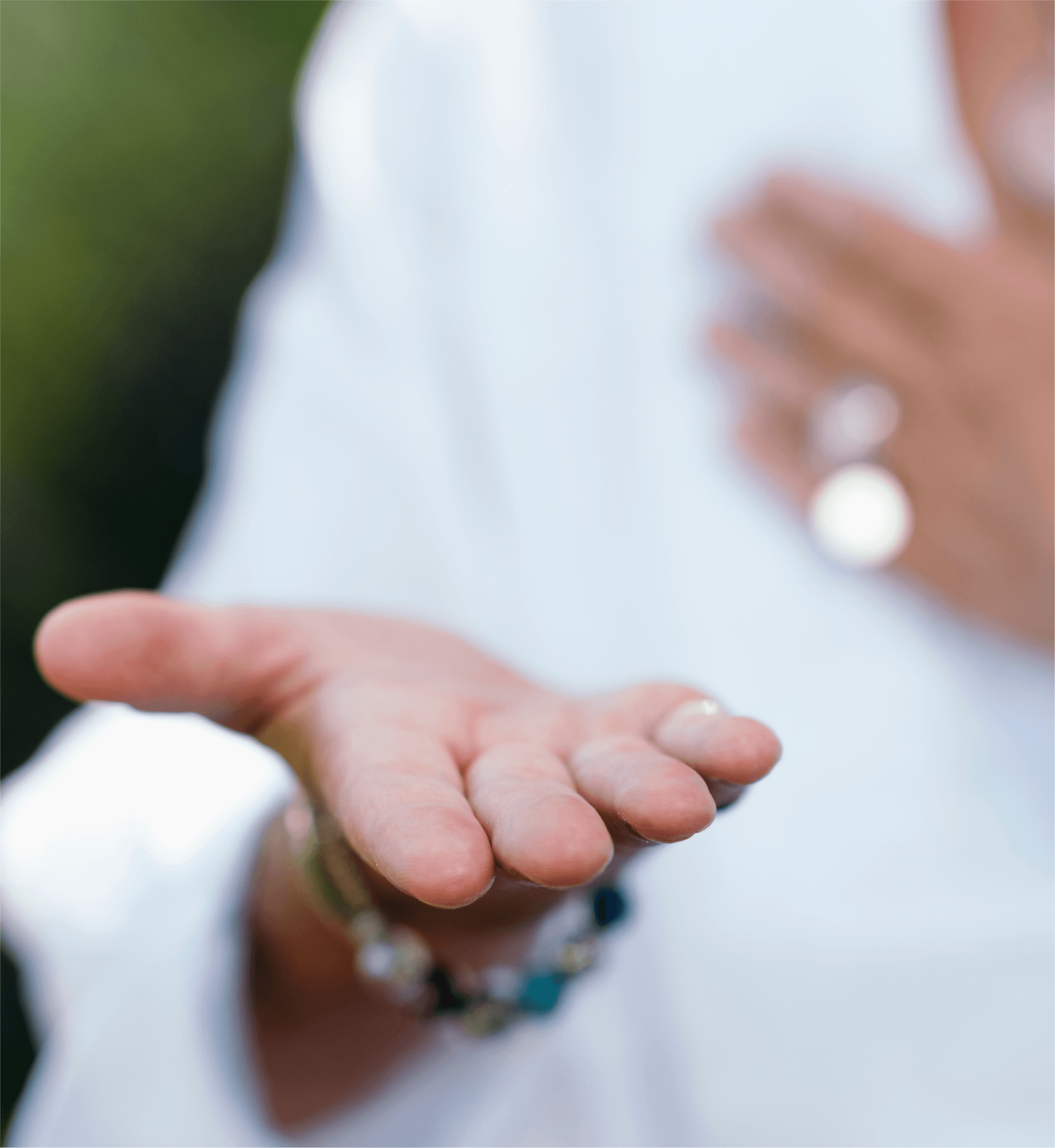 A woman is holding her hands out in front of a tree, offering spiritual healing and channeling energies.