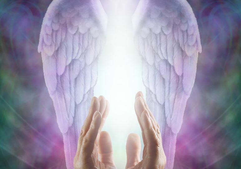 A pair of hands with angel wings providing spiritual healing in front of a colorful background.