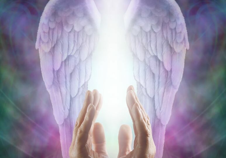 A pair of hands with angel wings providing spiritual healing in front of a colorful background.